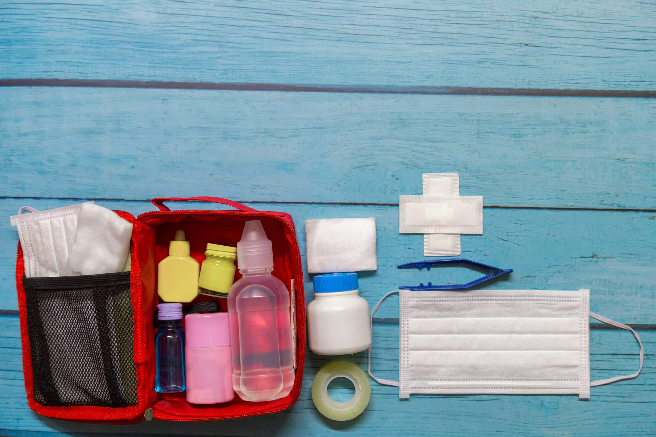 Top view first aid bag kid with medical supplies on wood background.