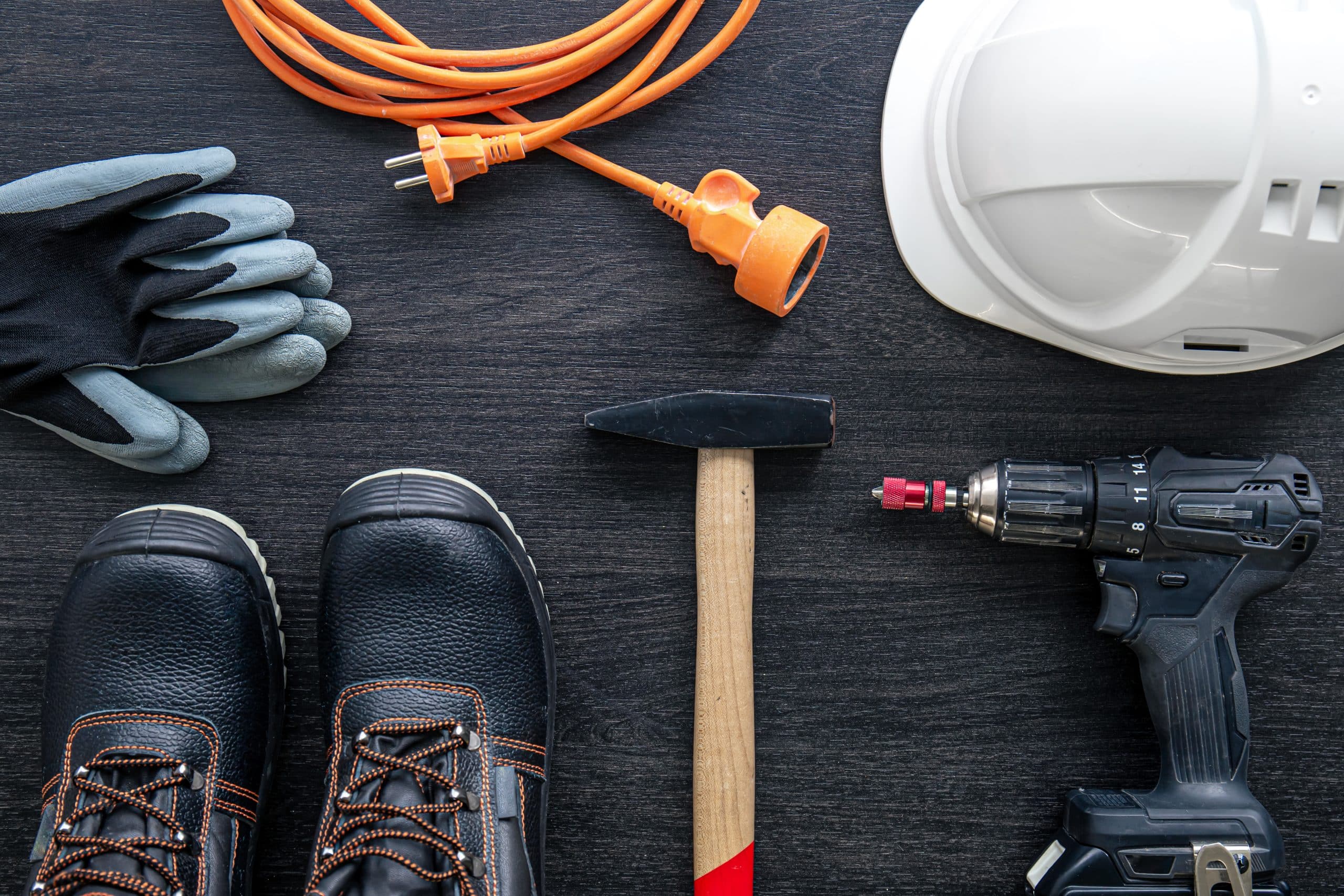 Working tools and things of a worker, builder or electrician, top view on a wooden background.